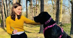 Jeune femme avec un carnet, assise à côté d'un grand chien noir