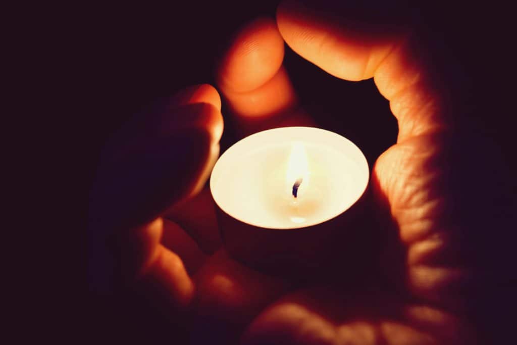 pexels-photo-331209-331209 A pair of hands cradling a candle creating a soft and warm illumination.