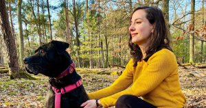 femme caucasienne assise dans la forêt avec un grand chien noir