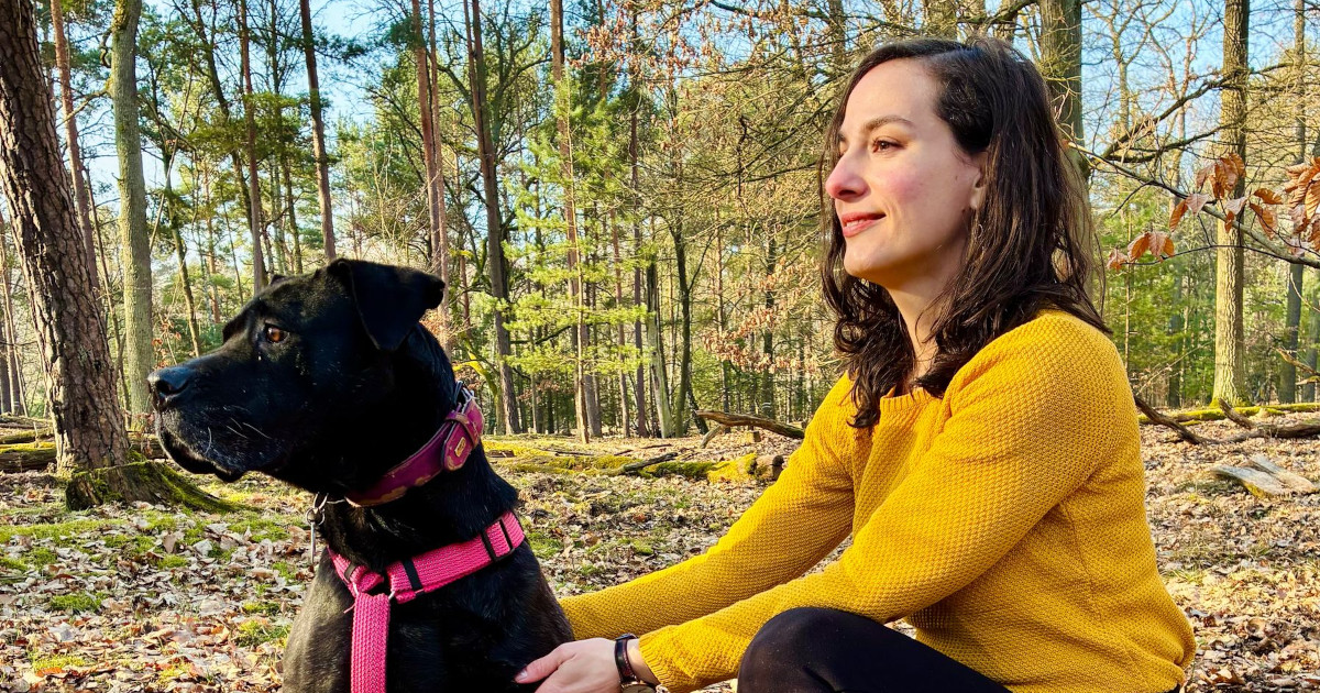 femme caucasienne assise dans la forêt avec un grand chien noir